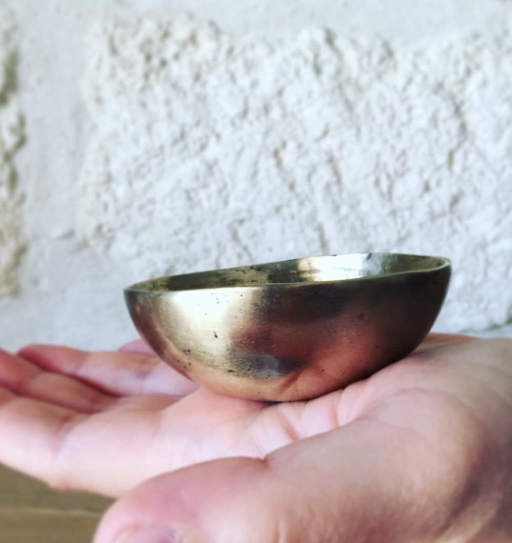 Le bol Kansu, utilisé dans la médecine ayurvédique, est un petit bol traditionnel en alliage de cuivre, de zinc, et de bronze. Il est employé pour des massages spécifiques des pieds, destinés à équilibrer les énergies du corps. Sur la photo, on peut voir un bol Kansu posé sur une main. Ce bol est utilisé pour masser la plante des pieds en effectuant des mouvements circulaires, favorisant la détente, l'amélioration de la circulation sanguine, et l'apaisement du mental.